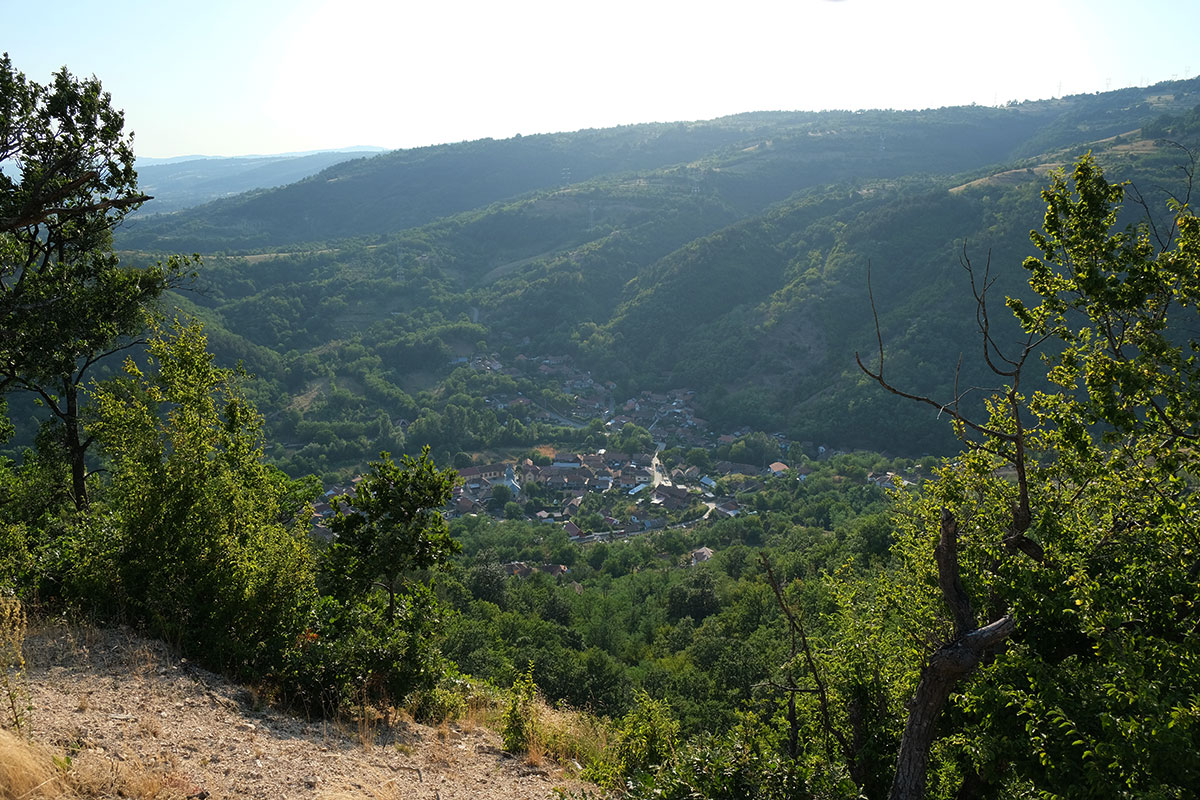 Blick von einem Berg auf ein Dorf in einem Talkessel