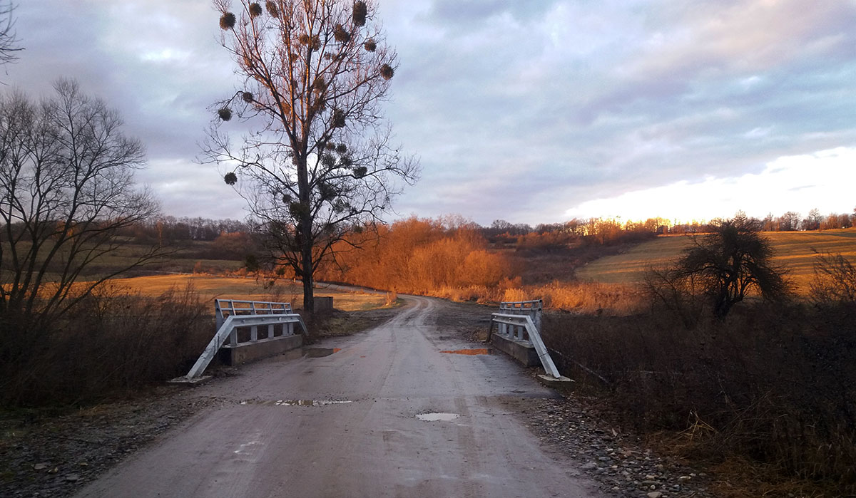 neue Dorfbrücke mit unbefestigter Straße davor und dahinter