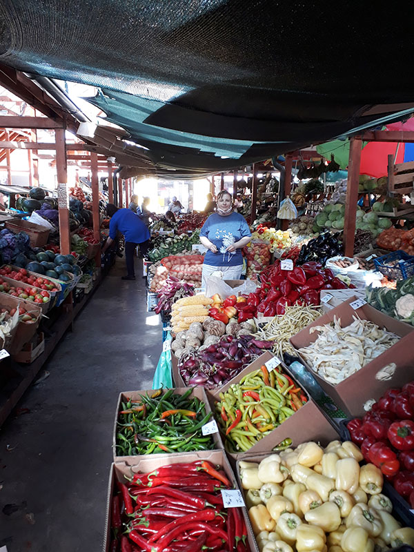 Frau steht im Markt neben Gemüseständen