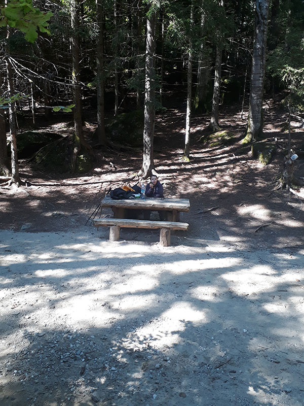 Frau sitzt auf einer Holzbank im Schatten