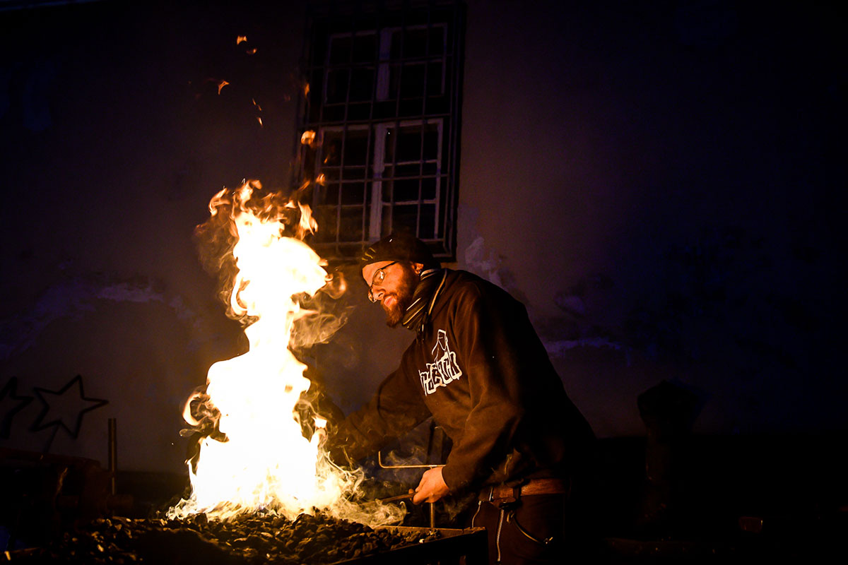 Mann steht neben einem Feuer