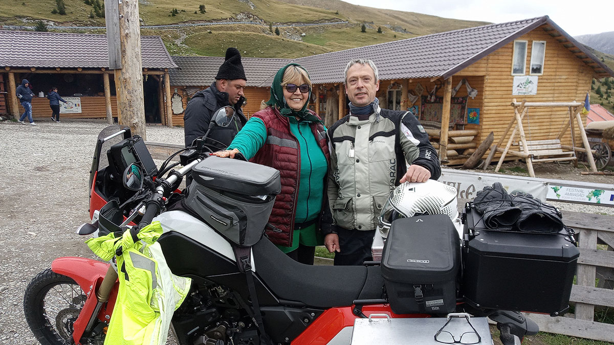 Motoradfahrer posiert mit Ehepaar neben seinem Motorrad stehend