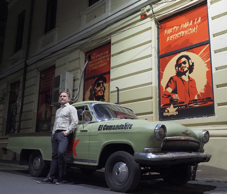 Männer fotografieren Mann vor einem Auto