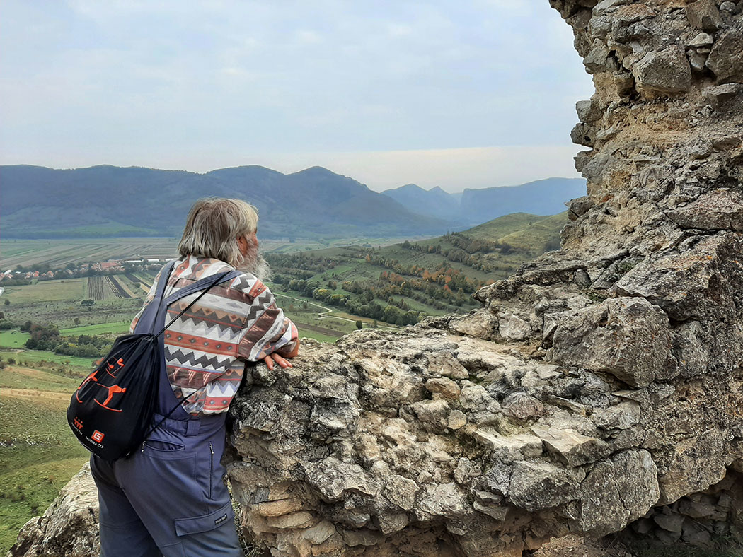 Mann steht an einer Mauer vor Berglandschaft