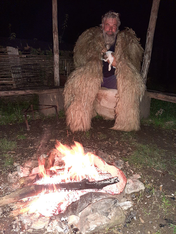 Mann am Feuer mit Schaffellumhang