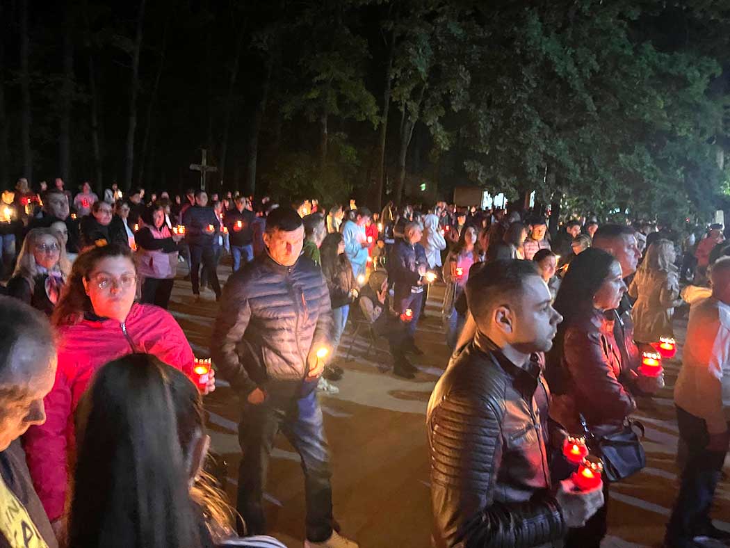 Menschen stehen mit Kerzen im Freien