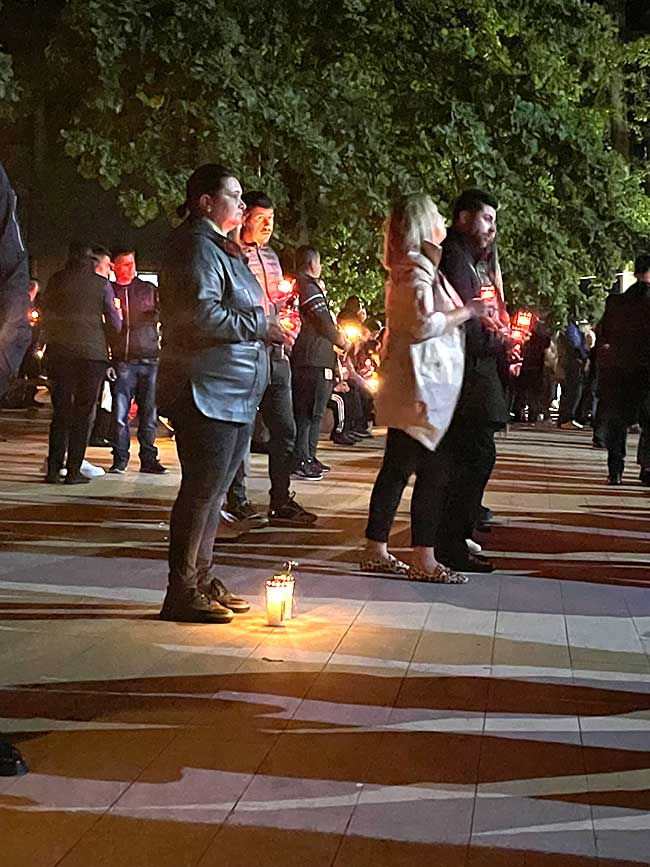 Menschen stehen mit Kerzen im Freien