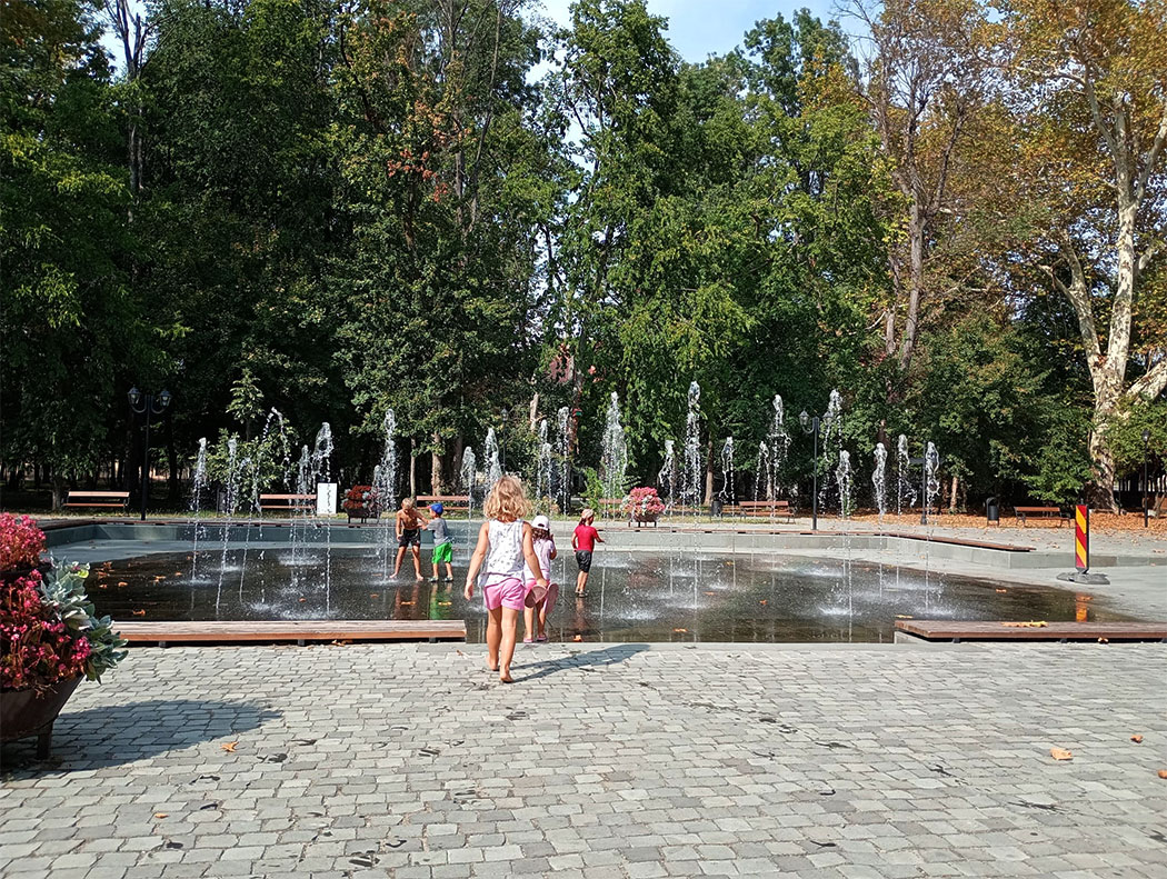 Kinder spielen an einem Springbrunnen