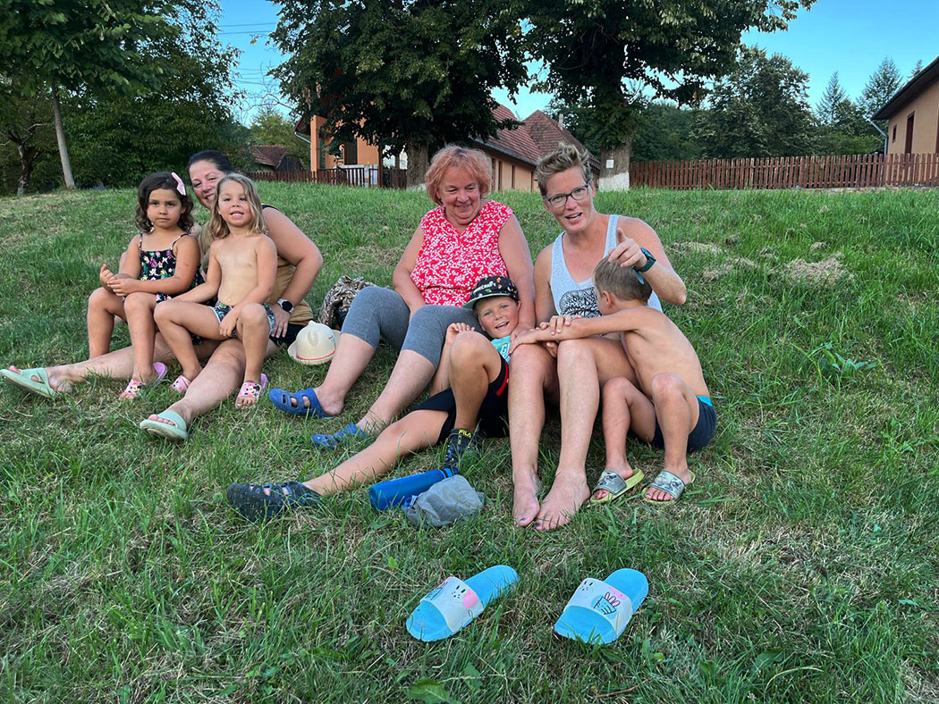 Kinder und Erwachsene sitzen auf einer Wiese