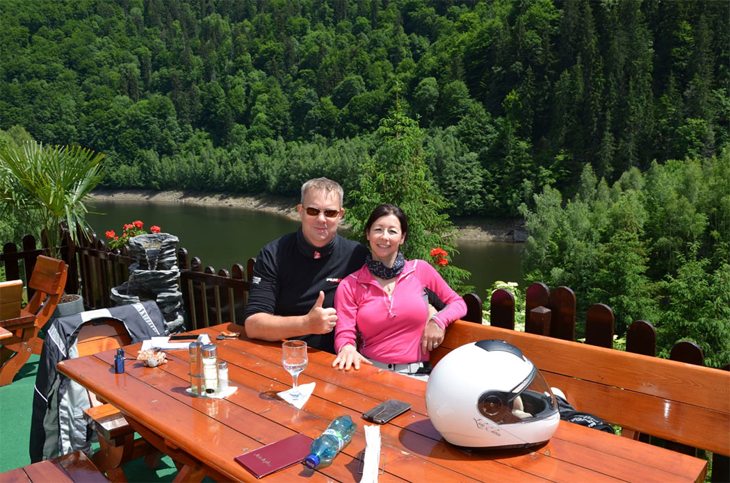 Paar in Motorradkleidung auf einer Bank sitzend