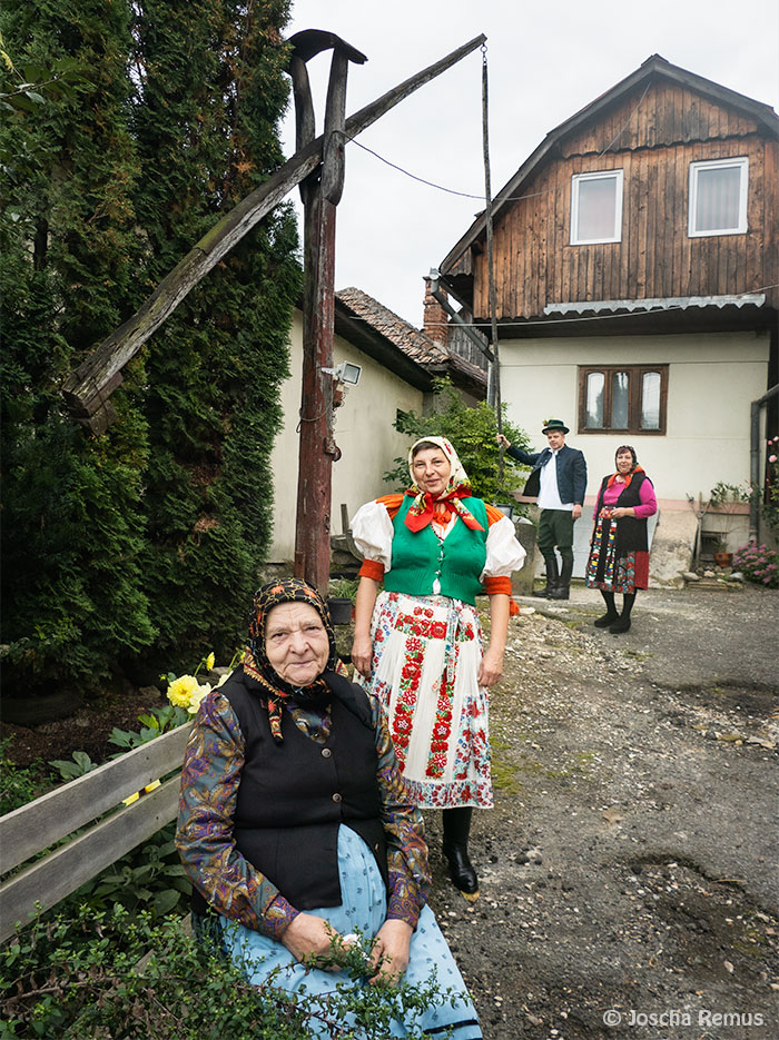 Männer und Frauen sitzen und stehen in Trachten in einem Hinterhof