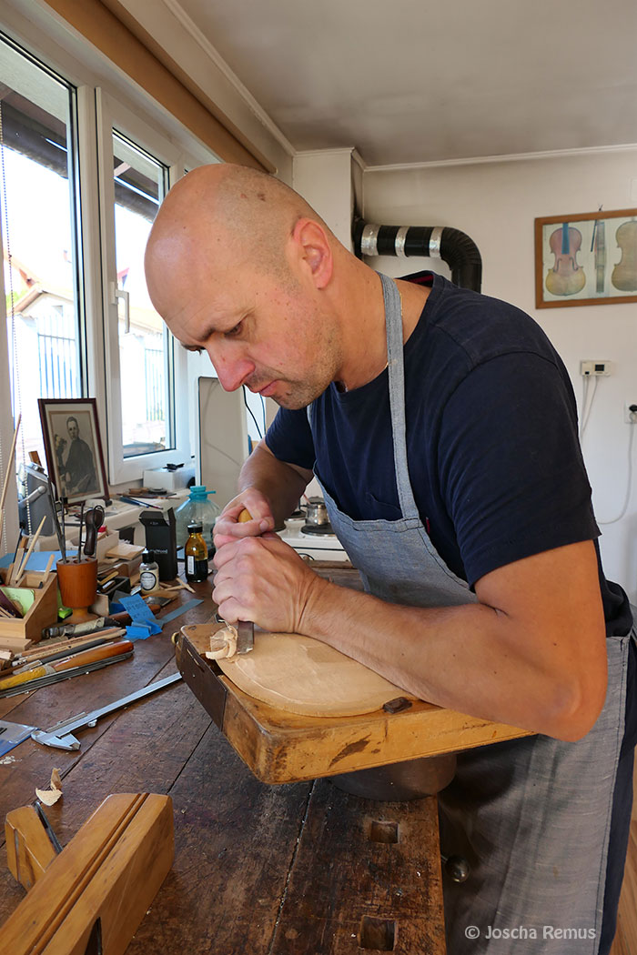 Mann bearbeitet ein Holzstück an einer Werkbank