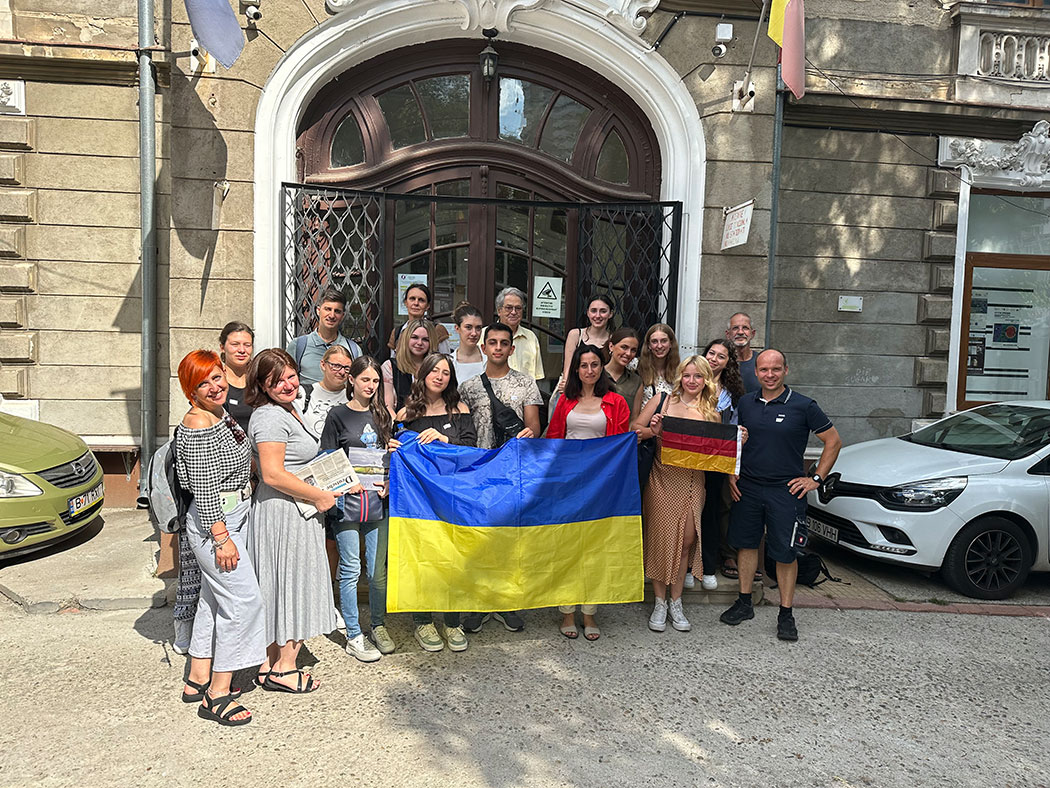 Menschen mit einer Ukrainefahne vor einem Haus
