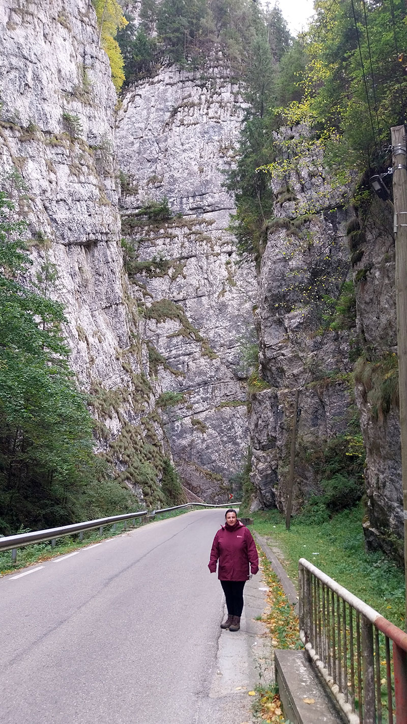 Frau steht auf einer Straße in einer Bergschlucht