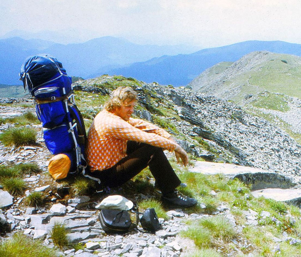 Mann sitzt mit Rucksack in Berglandschaft