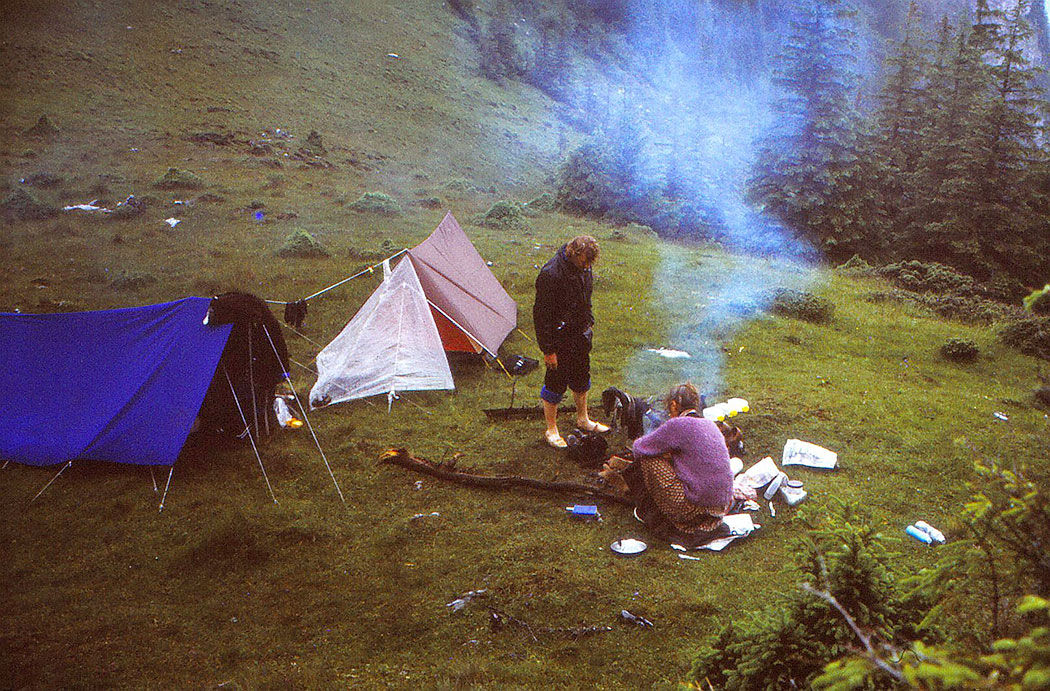 Menschen kochen vor Zelten auf einer Wiese