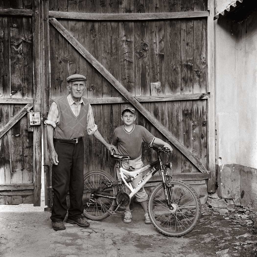 schwarz-weiß Portrait eines alten Mannes und eines Jungen vor einem Fahrrad