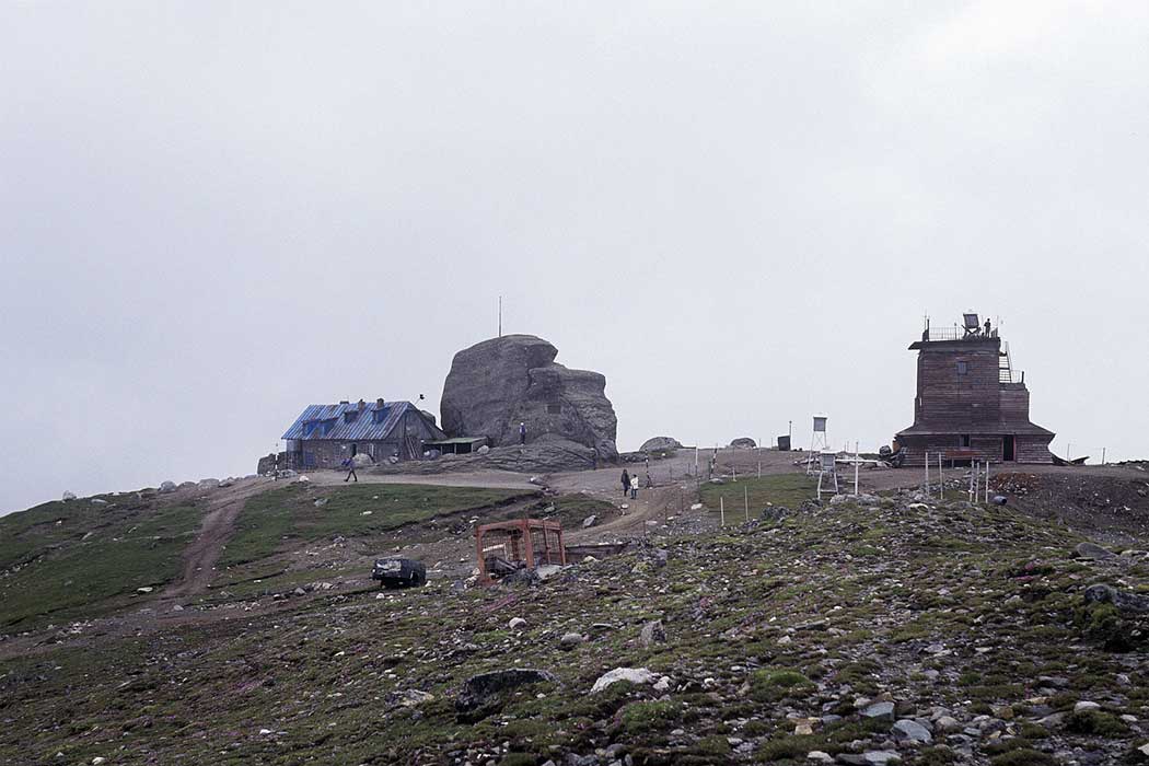 Berggipfel mit Felsen und zwei Häusern