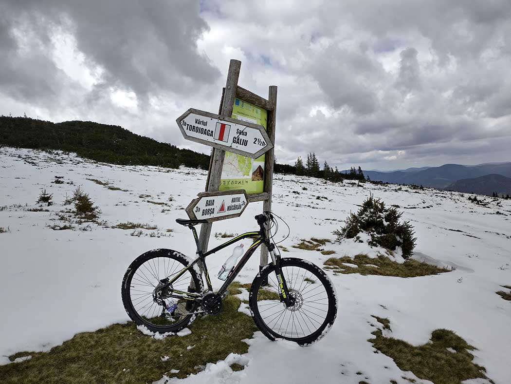 winterlicher Berglandschaft mit Wegweiser und Fahrrad