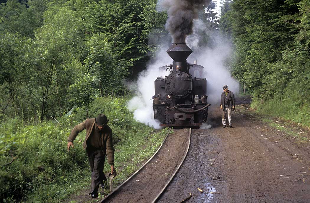 Mann streut Sand vor einer Dampflok