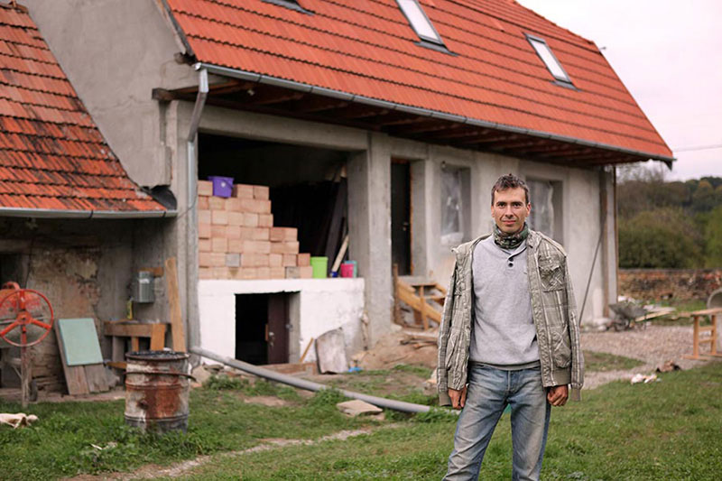 Mann steht vor einem Haus